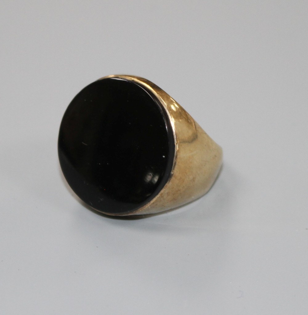 A yellow metal (stamped 9ct) and black onyx set circular signet ring, size L, gross weight 9 grams.